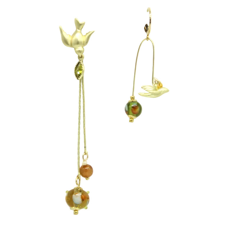 Boucles d'oreilles asymétriques Salvia en acier doré avec motifs d'oiseaux, chaînes pendantes et perles en verre de Murano olive et topaz.