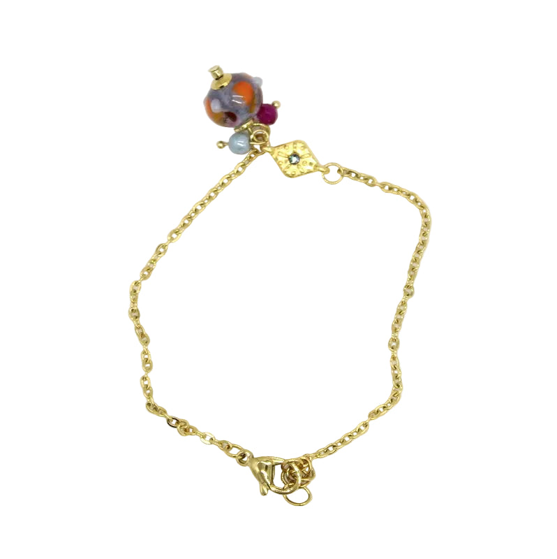 Bracelet fin en chaîne d'acier doré orné d'un motif losange texturé et de charms avec perle en verre de Murano bleue.