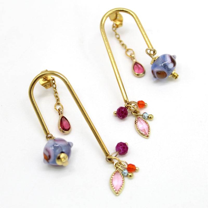 Gros plan Paire de boucles d'oreilles ponts puces en acier doré avec une perle en verre de Murano bleue et de charmantes pampilles colorées suspendues