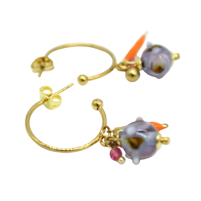 Gros plan Paire de créoles ouvertes en acier doré ornées d'un charm pendant avec perle en verre de Murano bleue et pampilles orangées.